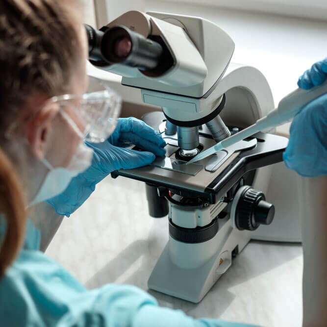 Female lab tech looking through microscope